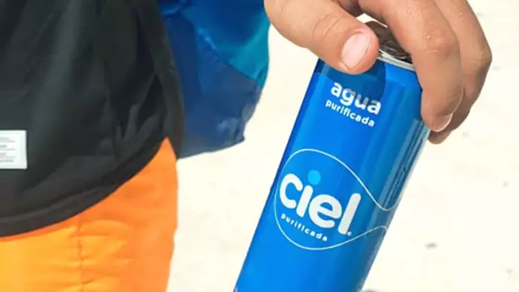 Person holding a blue water bottle labeled "agua purificada" against a light background Person holding a blue water bottle labeled "agua purificada" against a light background