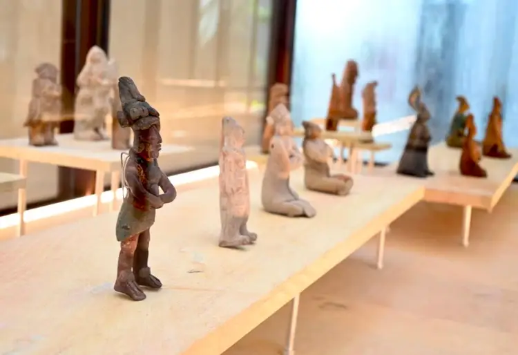Ancient figurines displayed on a museum shelf under gallery lighting Ancient figurines displayed on a museum shelf under gallery lighting