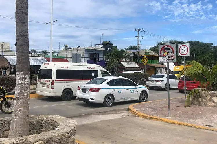 A white taxi and ambulance parked on a street lined with palm trees, utility poles, and commercial buildings under partly cloudy skies A white taxi and ambulance parked on a street lined with palm trees, utility poles, and commercial buildings under partly cloudy skies