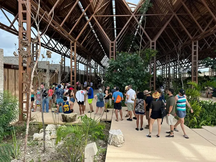 Visitors walk through a covered garden pathway with wooden lattice structures and tropical plants growing overhead Visitors walk through a covered garden pathway with wooden lattice structures and tropical plants growing overhead