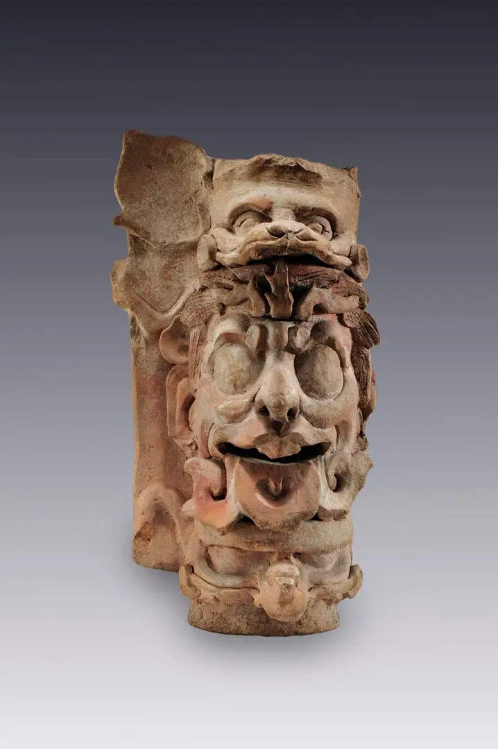 Stone carved architectural ornament featuring a bearded face with exaggerated features against a neutral background