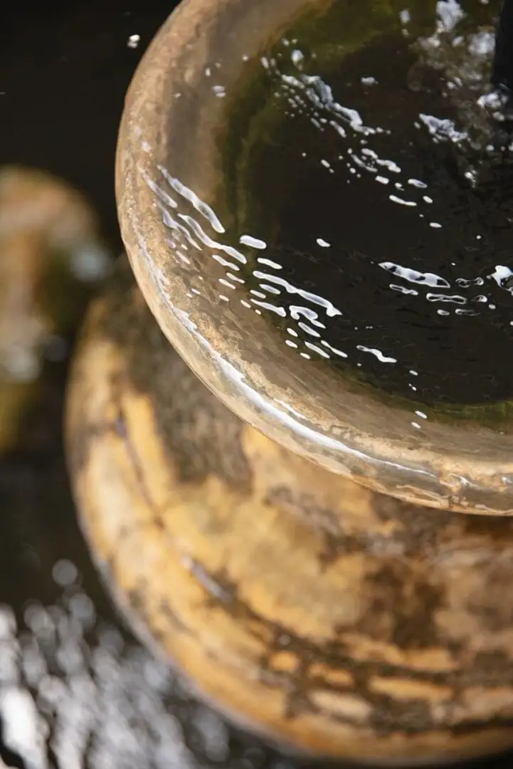 Water splashes into a ceramic bowl with moss-covered exterior against a dark background Water splashes into a ceramic bowl with moss-covered exterior against a dark background