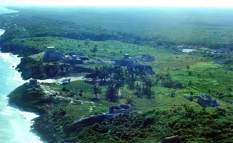 Aerial view of a coastal settlement with turquoise waters, palm trees, and green landscape dotted with buildings and structures Aerial view of a coastal settlement with turquoise waters, palm trees, and green landscape dotted with buildings and structures