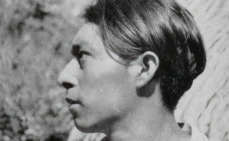 Profile view of a young man with dark hair looking toward a textured wall or surface Profile view of a young man with dark hair looking toward a textured wall or surface