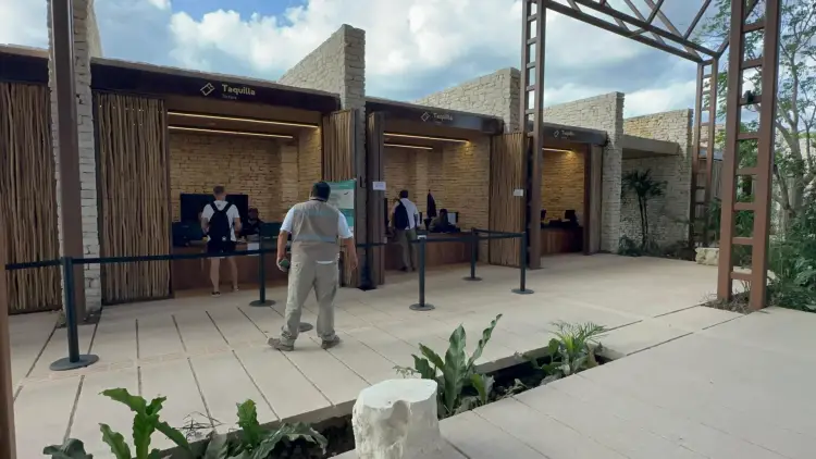 Man walks past ticket booths at an outdoor venue with stone walls and landscaping under a partly cloudy sky Man walks past ticket booths at an outdoor venue with stone walls and landscaping under a partly cloudy sky