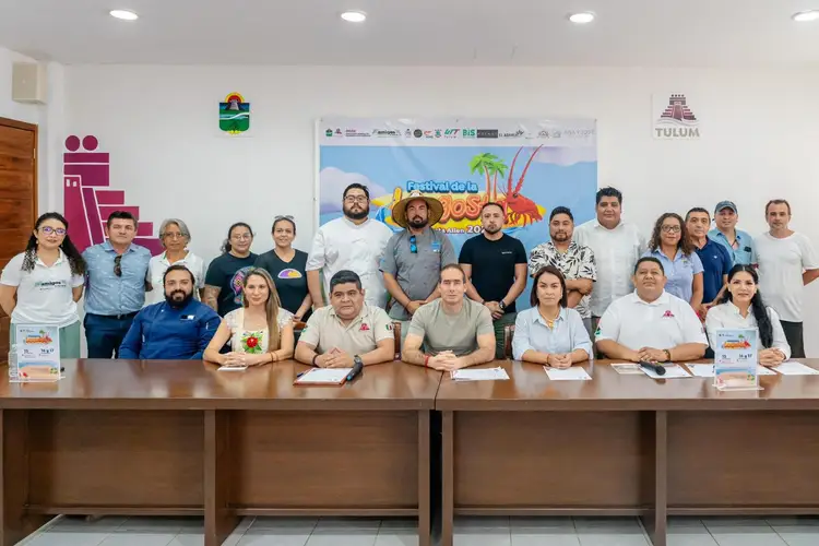 Group of people posing together at a table during what appears to be a festival planning or promotional event in an indoor venue Group of people posing together at a table during what appears to be a festival planning or promotional event in an indoor venue