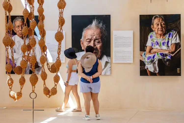 Child viewing portrait photographs and woven fiber sculptures hanging in a gallery space Child viewing portrait photographs and woven fiber sculptures hanging in a gallery space