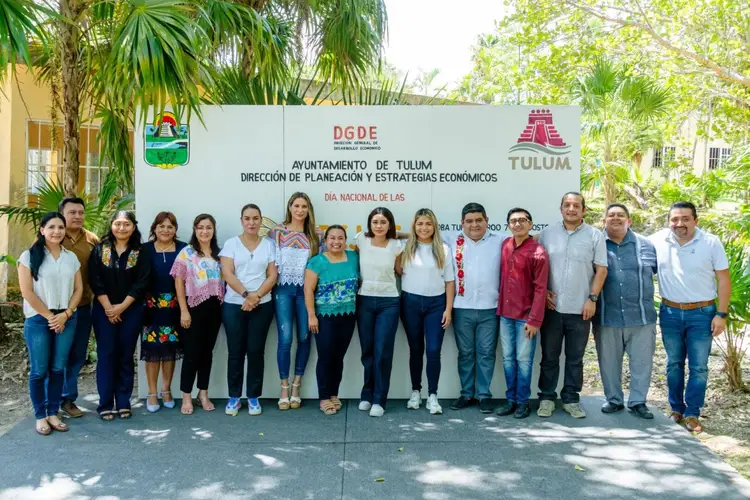 Group of government officials and staff members stand in a line in front of a municipal building sign in a tropical setting Group of government officials and staff members stand in a line in front of a municipal building sign in a tropical setting