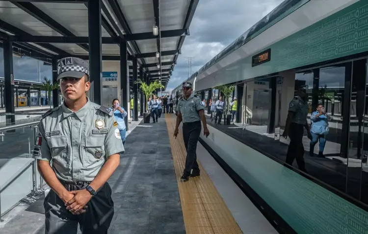 Transit police officer stands on a train platform while passengers board a modern passenger train at a station Transit police officer stands on a train platform while passengers board a modern passenger train at a station