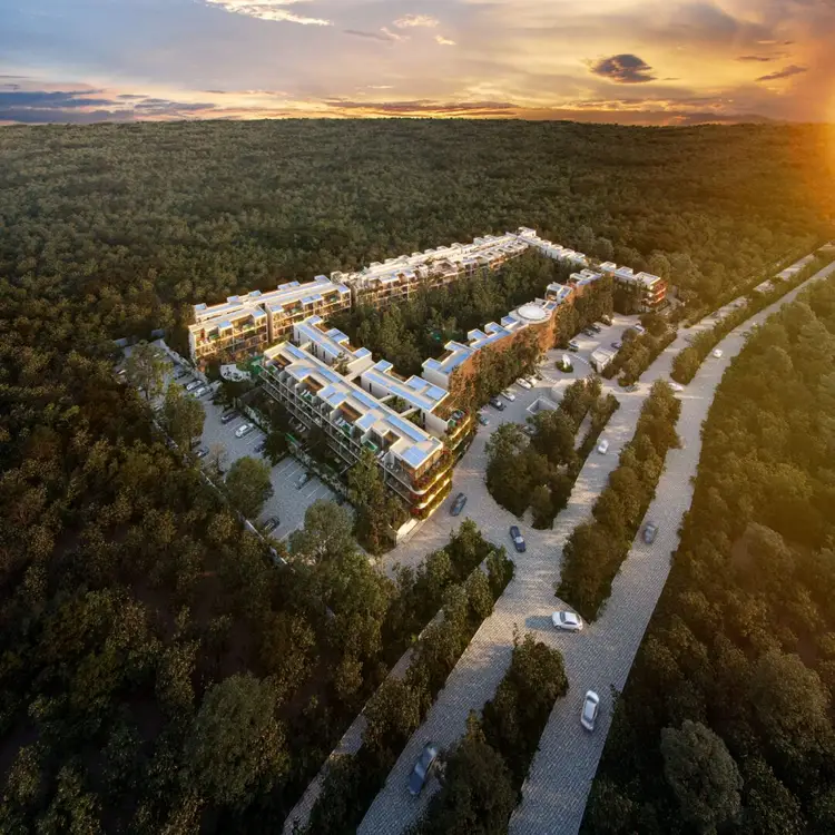 Aerial view of a modern multi-building residential complex surrounded by dense forest with organized parking areas and tree-lined roads at sunset Aerial view of a modern multi-building residential complex surrounded by dense forest with organized parking areas and tree-lined roads at sunset