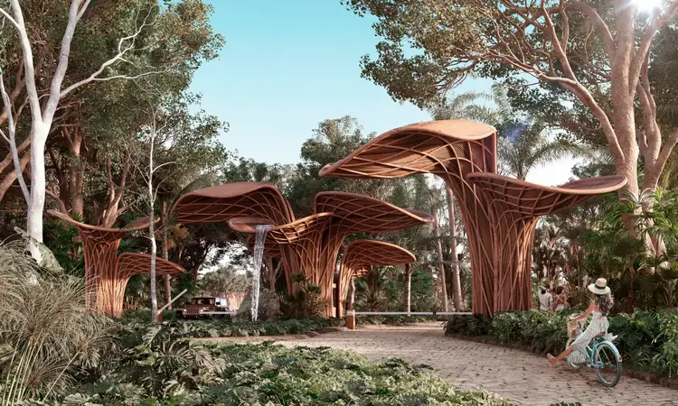 Wooden sculptural shade structures line a paved pathway through a landscaped garden with tall trees and tropical plants, while a person on a bicycle passes by