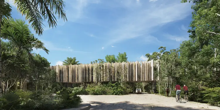 Modern wooden structure with vertical slats surrounded by tropical vegetation and trees, with visitors on a sandy path in the foreground