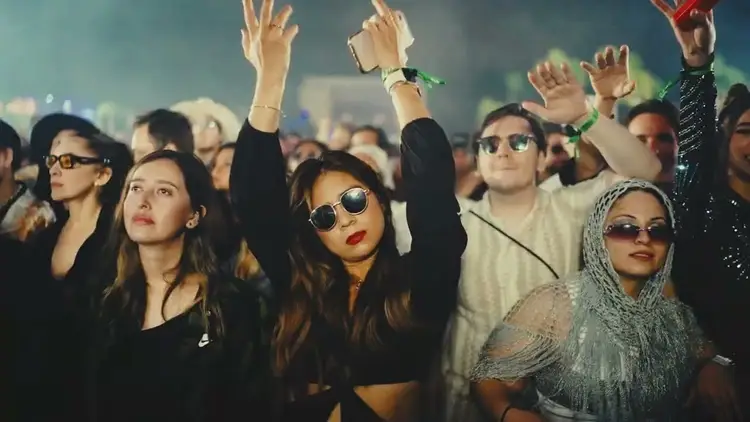 Crowd of concertgoers with raised hands watching a performance at an outdoor music festival at night Crowd of concertgoers with raised hands watching a performance at an outdoor music festival at night