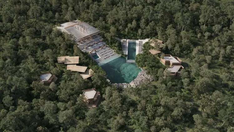Aerial view of a resort development with a turquoise pool, wooden deck structures, and tan-colored buildings nestled among dense forest trees Aerial view of a resort development with a turquoise pool, wooden deck structures, and tan-colored buildings nestled among dense forest trees