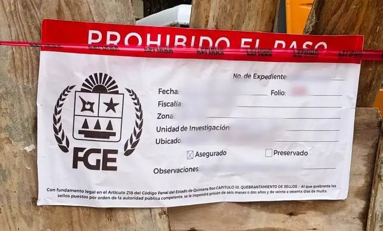 Official seal notice with "Prohibido el Paso" red tape attached to wooden surface, displaying FGE agency form with fields for case details and observations