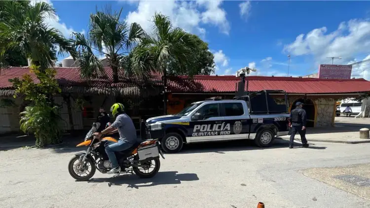 Police truck parked outside a building while a motorcyclist rides past on a street with palm trees