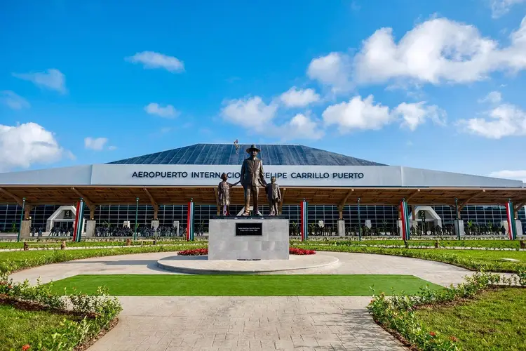 Equestrian statue stands in front of an airport terminal building with a metal roof under blue sky with white clouds Equestrian statue stands in front of an airport terminal building with a metal roof under blue sky with white clouds