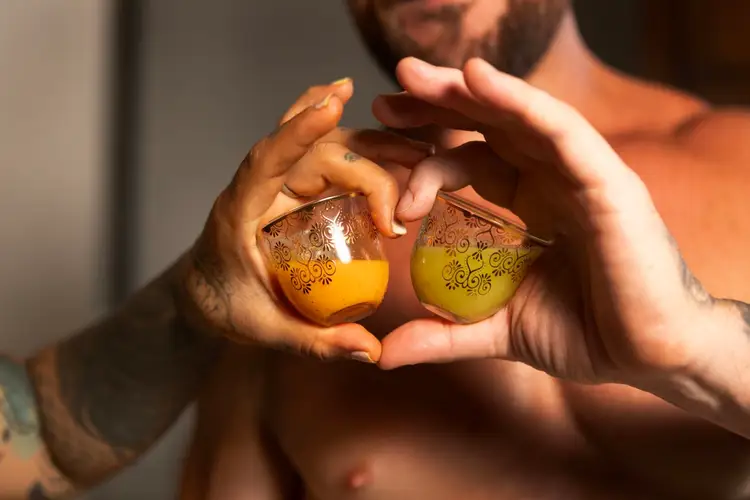 Person holding two decorative spheres with yellow and green liquid inside, forming a heart shape with their hands
