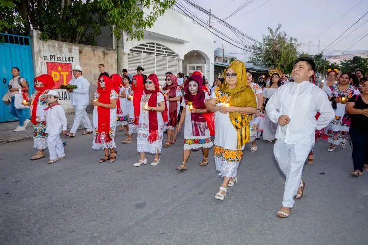 People in red and white traditional clothing parade down a street while spectators watch from the sides