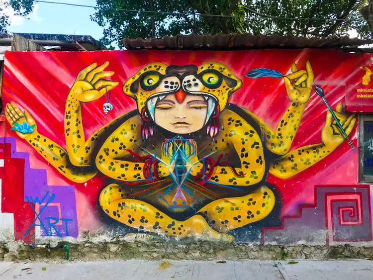 Mural of a stylized figure with yellow spotted tentacles and geometric patterns on a bright red wall