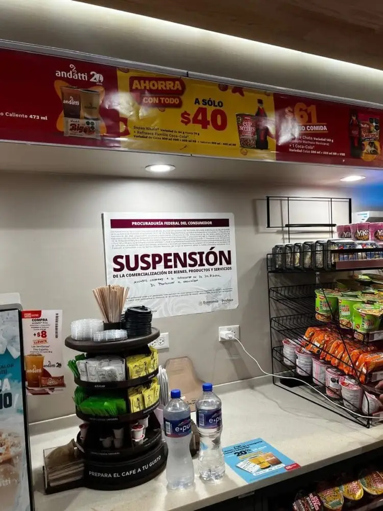 A store counter displays a suspension notice from federal consumer protection authorities posted on the wall above shelves of packaged goods and bottled water