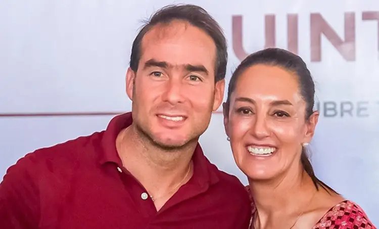 Two people smile at a media event with partially visible signage in the background Two people smile at a media event with partially visible signage in the background