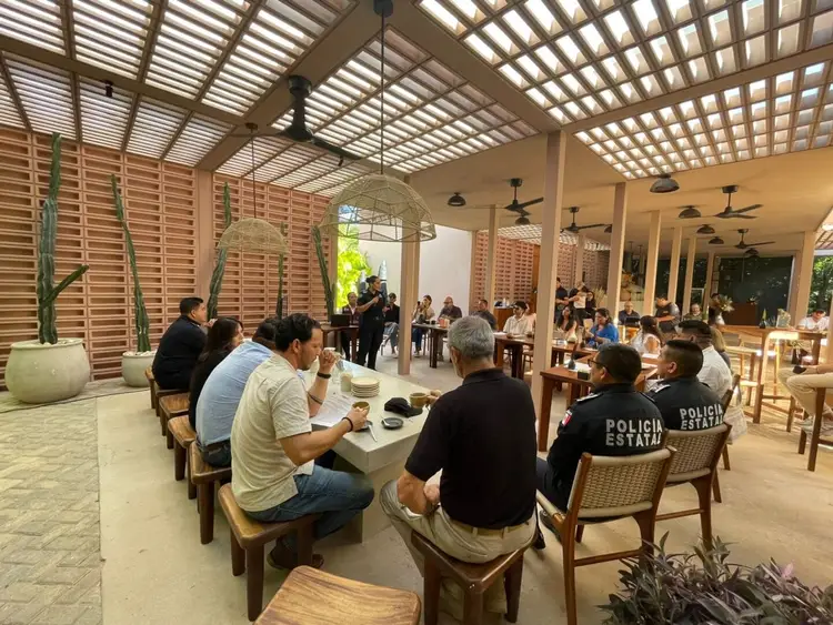 People seated at tables in an open-air covered pavilion during what appears to be a community meeting or discussion event
