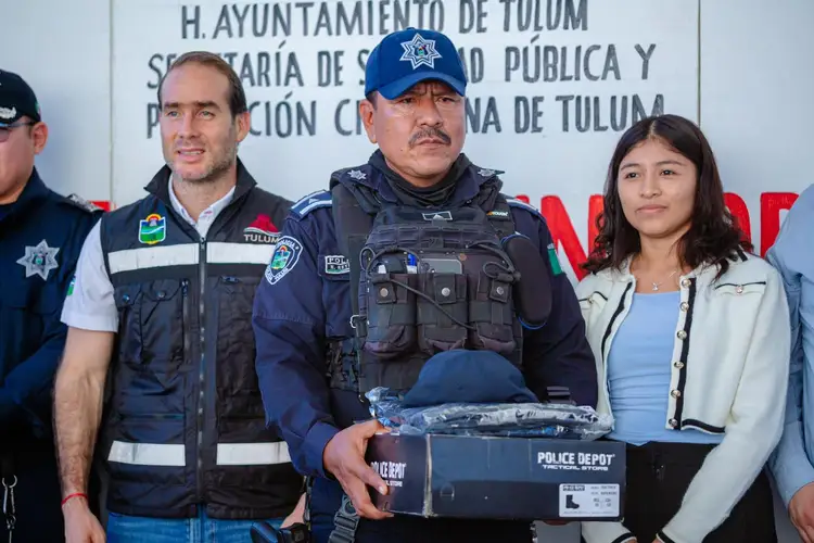 Police and municipal officials stand together displaying new uniforms and equipment at a public security event in Tulum