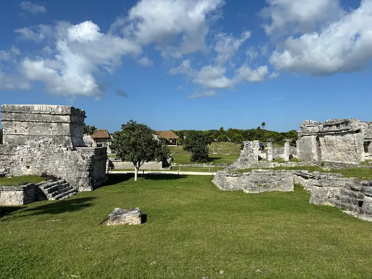 Ancient stone ruins with grassy grounds stand beneath a blue sky with white clouds Ancient stone ruins with grassy grounds stand beneath a blue sky with white clouds