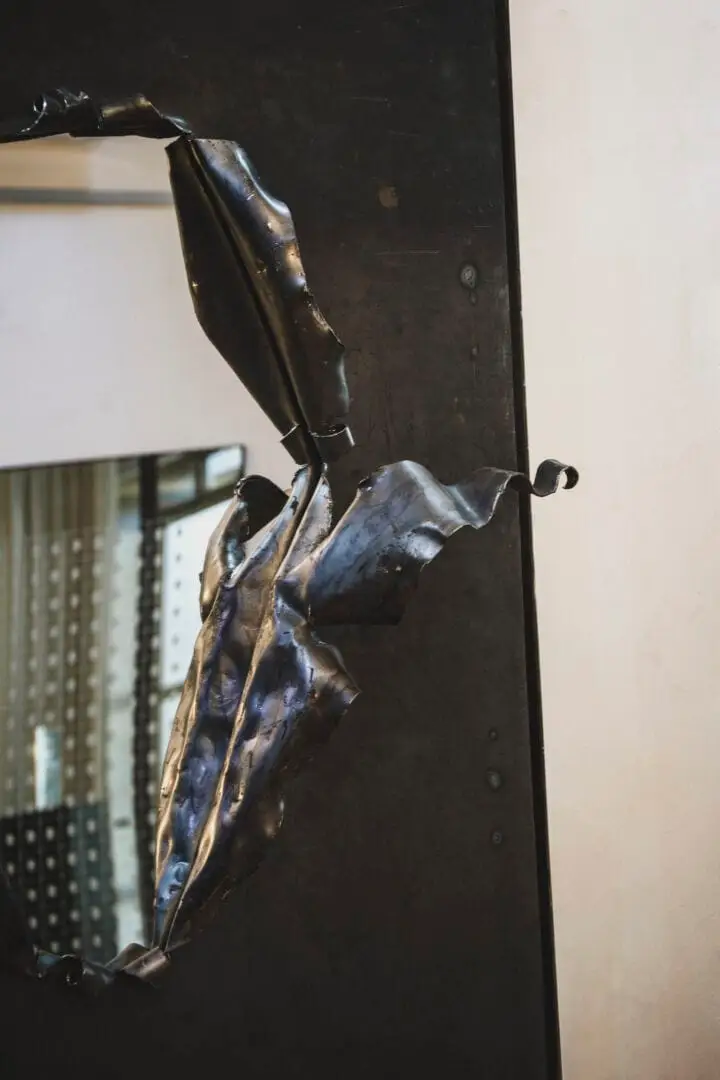 Bronze sculpture of an abstracted human figure mounted on a dark wall in an interior space