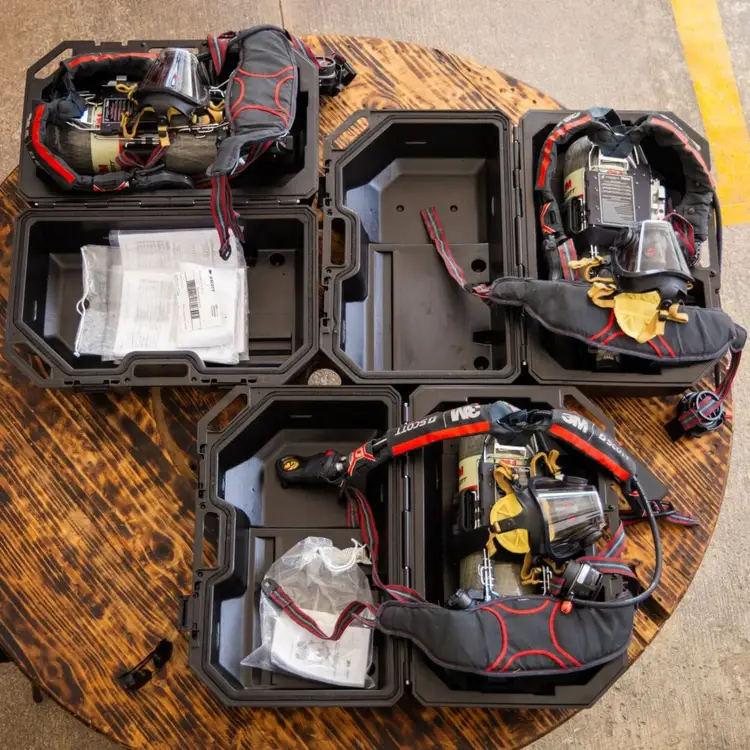 Open equipment cases containing tool bags, batteries, wiring, and instruction manuals arranged on a wooden pallet next to a yellow line Open equipment cases containing tool bags, batteries, wiring, and instruction manuals arranged on a wooden pallet next to a yellow line