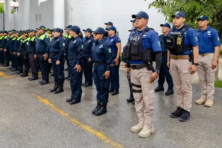 Large group of police officers in blue uniforms and caps stand in formation on a street next to a building
