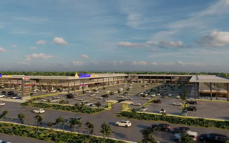 Aerial view of a large commercial complex with a multi-story shopping center, parking lot filled with vehicles, and landscaped grounds under blue sky with cloud Aerial view of a large commercial complex with a multi-story shopping center, parking lot filled with vehicles, and landscaped grounds under blue sky with cloud