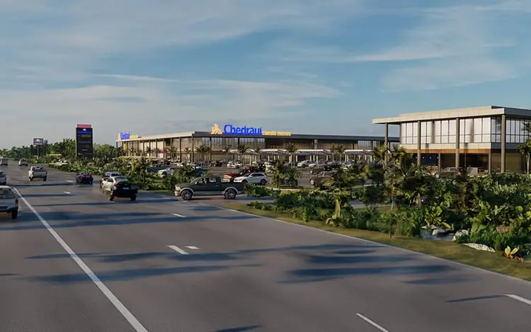 Large commercial building with blue signage sits beside a divided highway with moving vehicles and landscaping Large commercial building with blue signage sits beside a divided highway with moving vehicles and landscaping