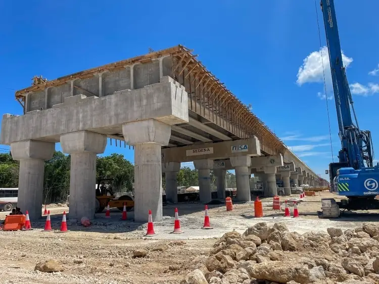 Elevated concrete highway bridge under construction with wooden framework on top, surrounded by safety cones and construction equipment on bare ground Elevated concrete highway bridge under construction with wooden framework on top, surrounded by safety cones and construction equipment on bare ground