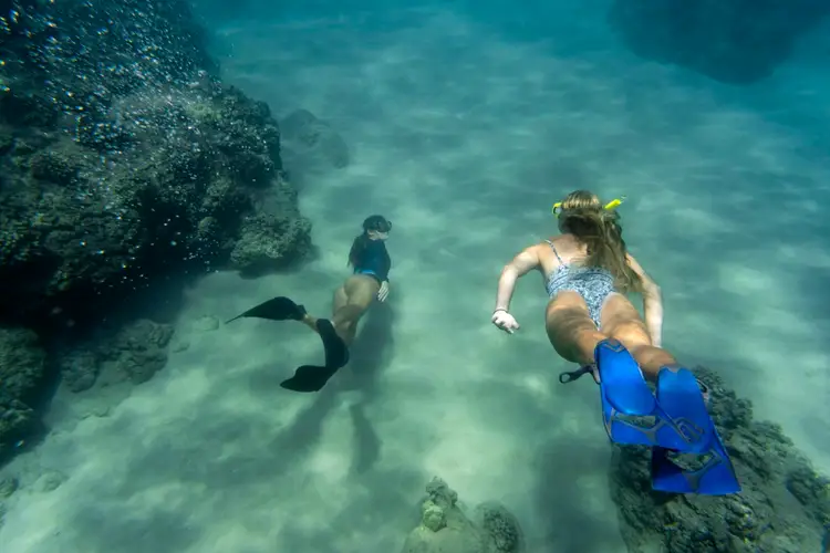 women-freediving-with-flippers-underwater