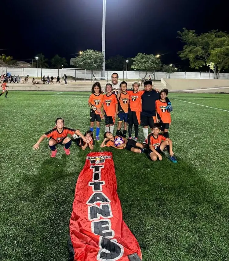 Youth soccer team poses on a night field with a red banner displaying their club name image10