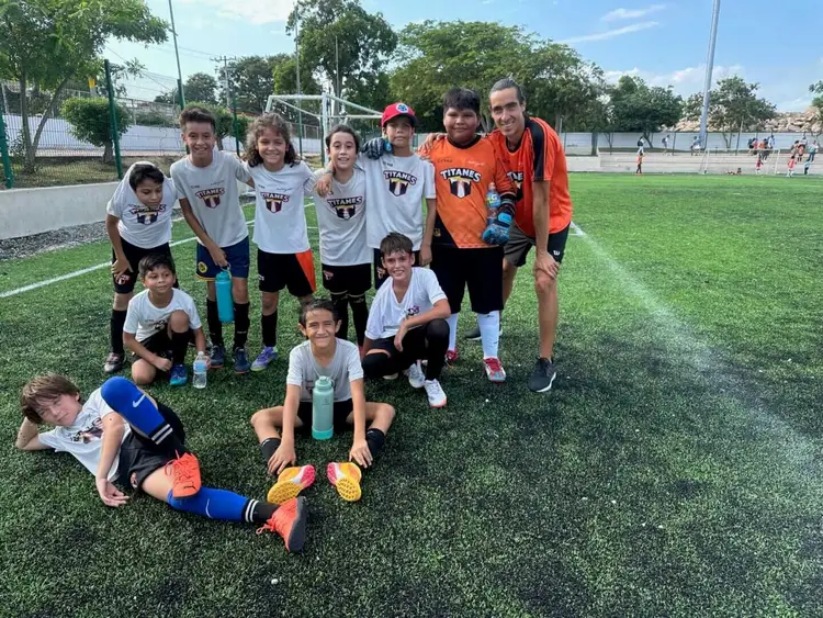 Youth soccer team members and coaches pose together on a grass field during practice image9
