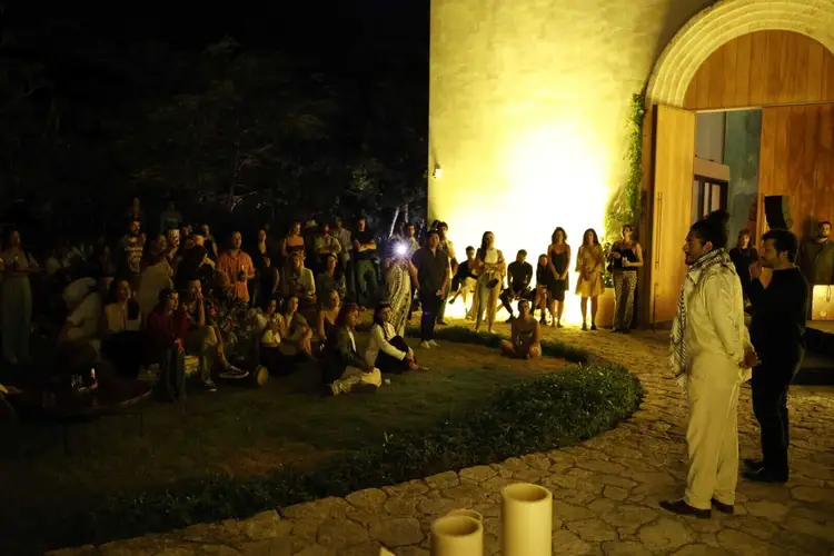 Crowd of people gathered at night outside an arched doorway of a stone building illuminated by yellow lighting _NF_2418