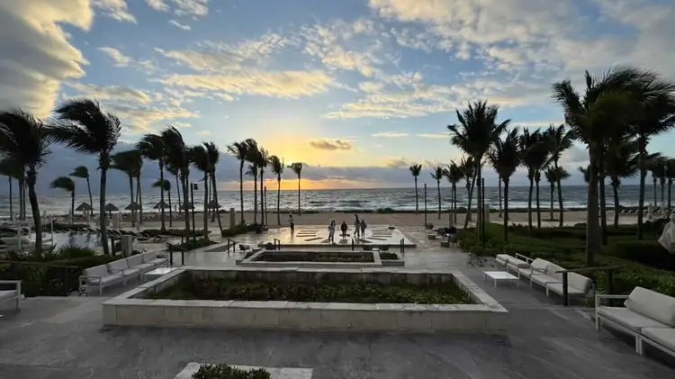 A beachfront resort courtyard with palm trees, lounge seating, and ocean view at dusk D68C868B-EFF9-48BC-A5B8-4BA202C0EBD3_1_105_c