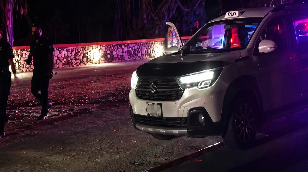 A Canadian citizen is among three held over a Tulum taxi driver's killing White taxi cab parked at night with a person standing nearby and illuminated buildings in the background