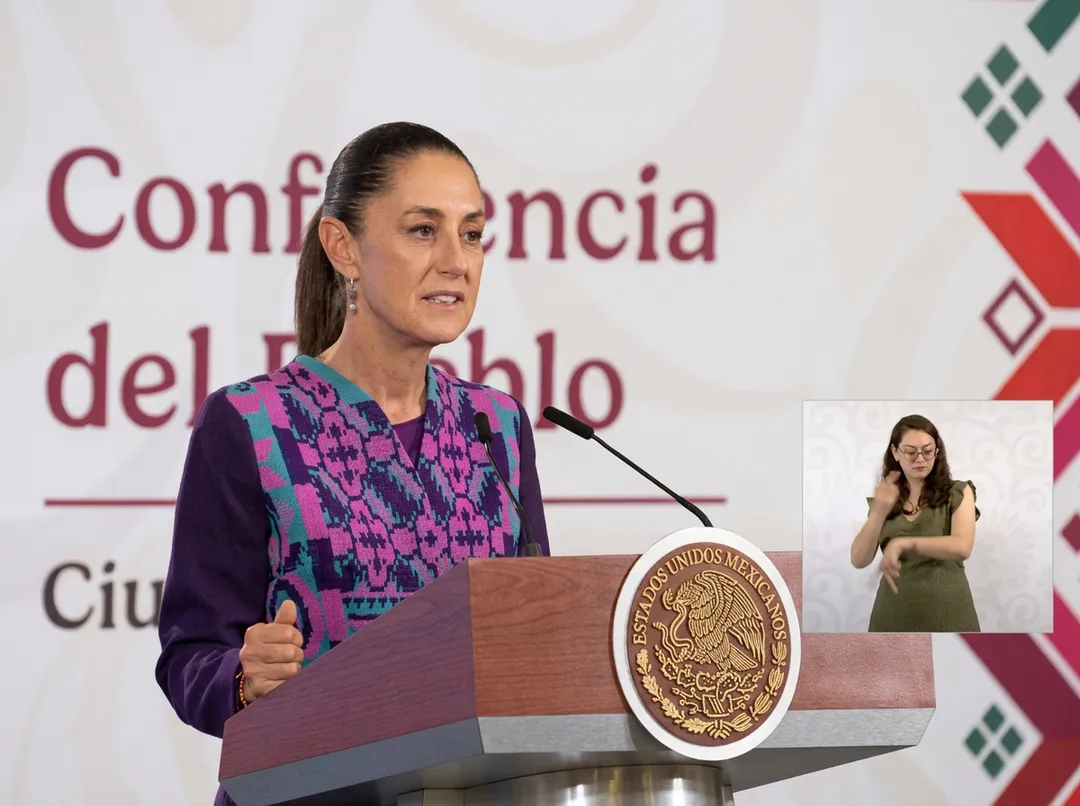 Woman speaking at a podium bearing the Mexican national seal during an official presentation, with a sign interpreter visible in the lower right corner