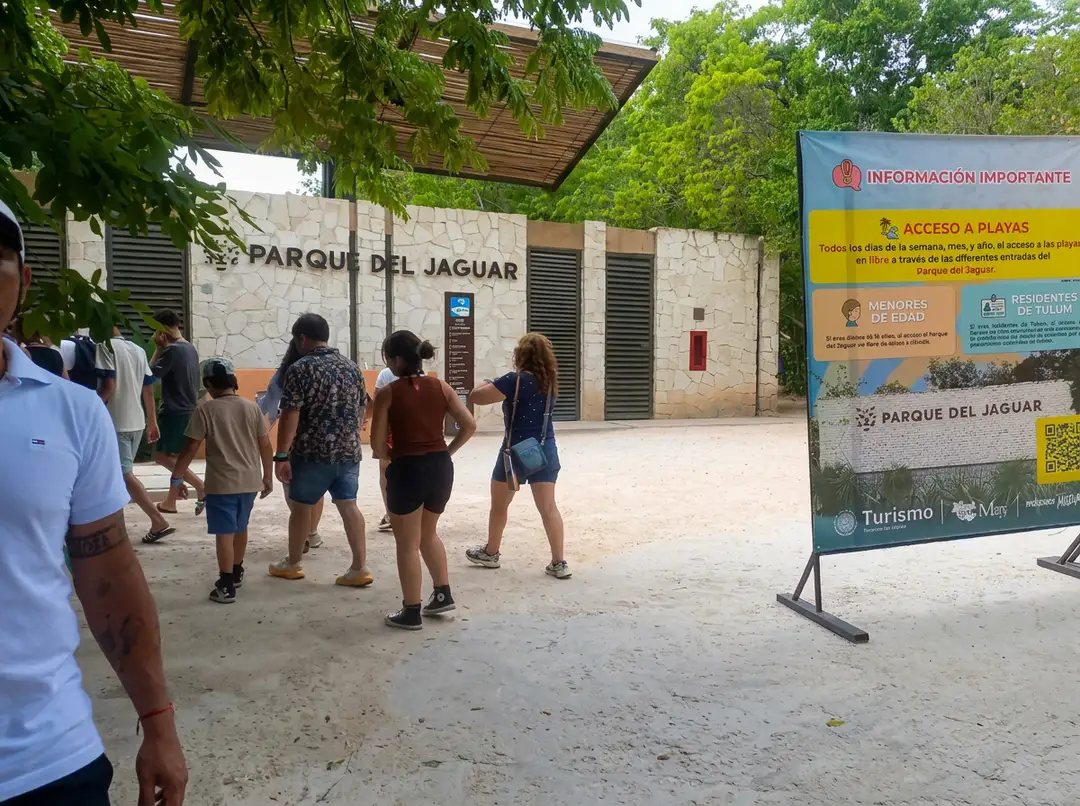 Visitors gather in a sandy courtyard at Parque del Jaguar with stone buildings and informational signage visible