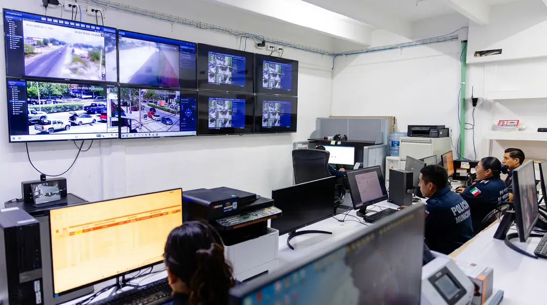 Security control room with multiple monitors displaying street camera feeds and several operators seated at workstations monitoring live footage