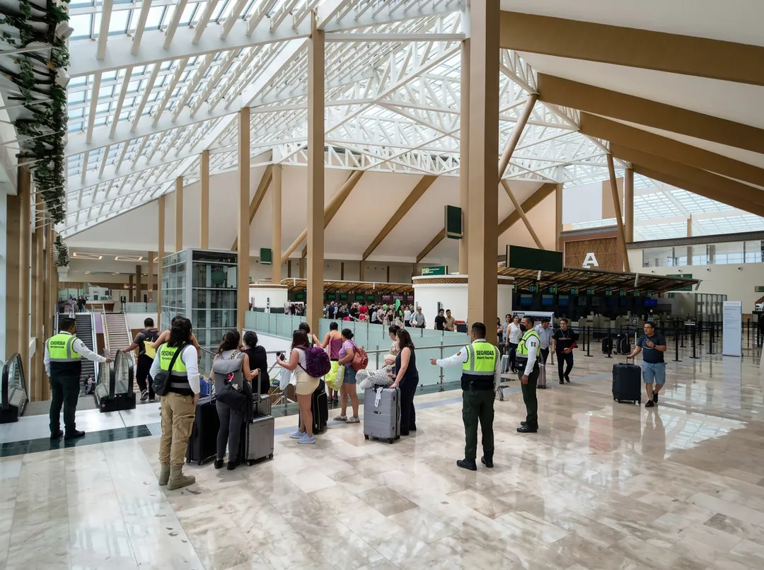 Tulum Felt a 6.1 Earthquake on June 8, 2026. No Injuries or Damage Were Reported Security personnel in yellow vests monitor travelers with luggage in a modern airport terminal with high ceilings and natural light