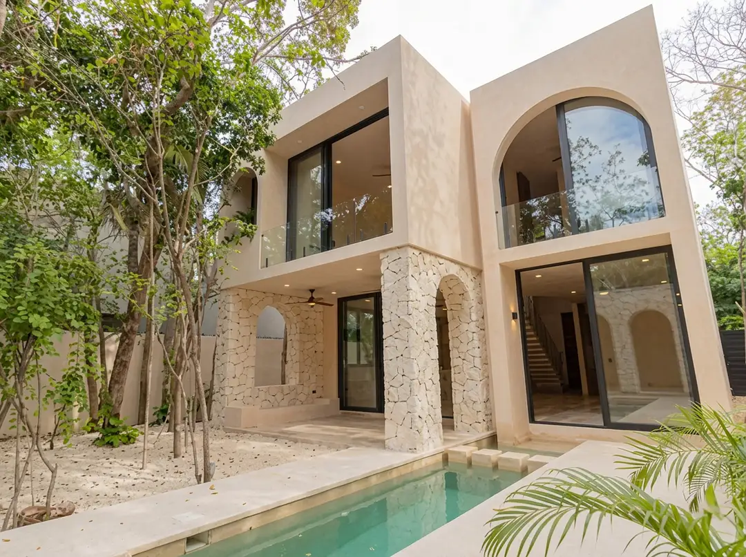 An apartment in central Tulum now costs more than the average Quintana Roo wage Modern two-story house with stone and stucco exterior, large windows, and a narrow pool in the courtyard surrounded by tropical vegetation