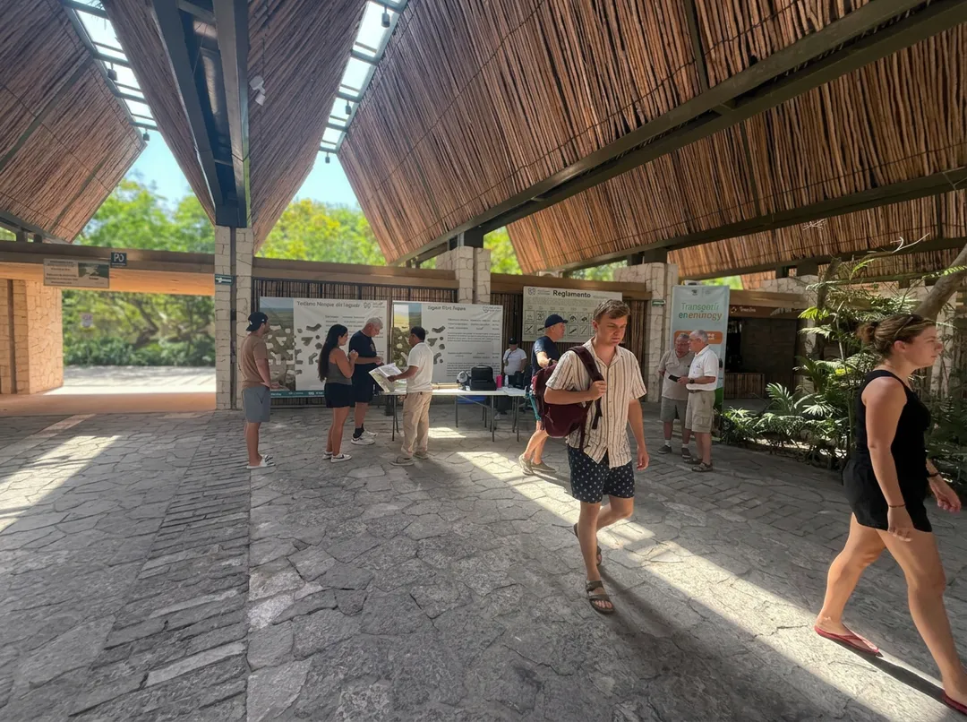Visitors walk through a covered outdoor pavilion with wooden slatted roof panels, viewing informational displays mounted on walls