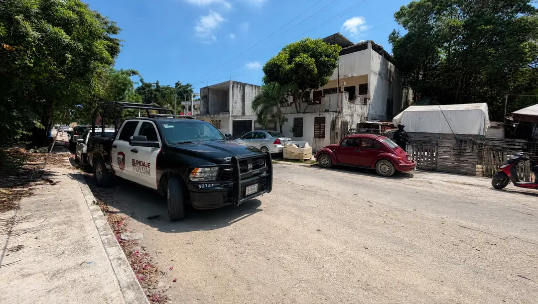 Police vehicle parked on a residential street with concrete buildings, palm trees, and other parked cars visible in the background