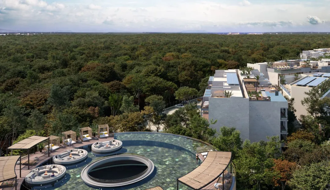 Oversupply in Tulum apartments creates opening for selective investors Aerial view of a modern resort with circular pools surrounded by forest and nearby white residential buildings under partly cloudy skies